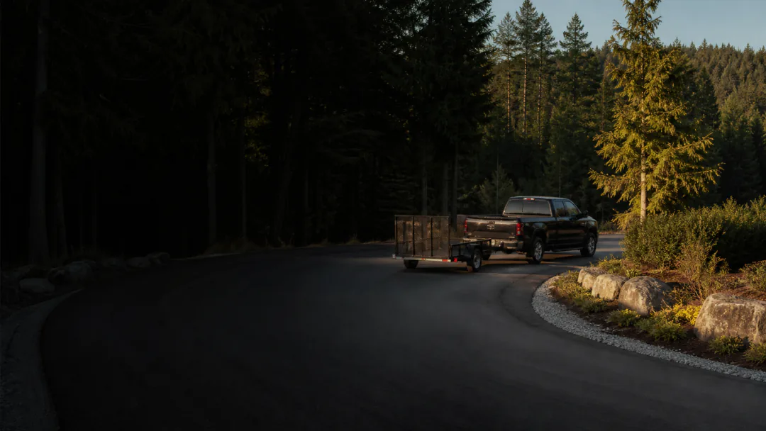 Pickup and utility trailer turning over an unconfined acreage driveway edge